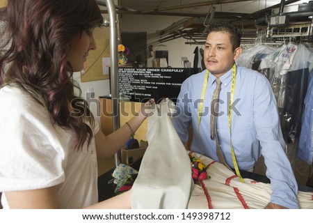 Young woman giving clothes for dry cleaning at laundry