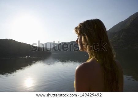 Blonde woman looking out across morning sunrise over lake