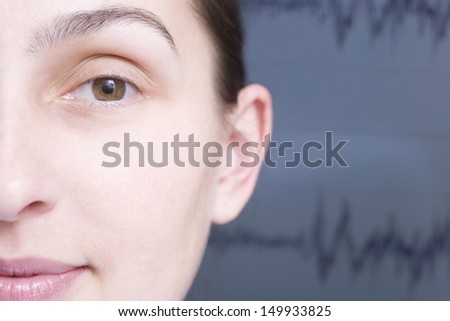 Closeup of cropped woman\'s face with blurred sound wave graph in background