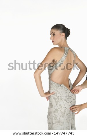 Beautiful young woman waiting for zip to be done up on backless dress against white background