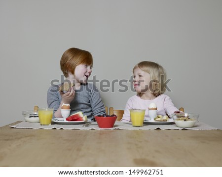 Two smiling sisters talking while eating breakfast together