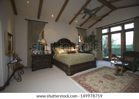 View of a spacious bedroom with beamed ceiling and patio doors