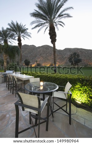 Patio chairs and tables against lawn and mountains in Palm Springs