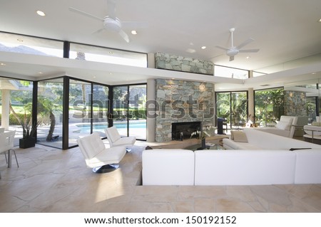 Sunken seating area and exposed stone fireplace in spacious living room with view of swimming pool at home