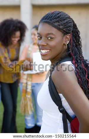 Portrait of female college student on campus with classmates in background