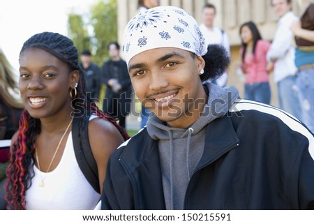 Portrait of young college students on campus with classmates in background