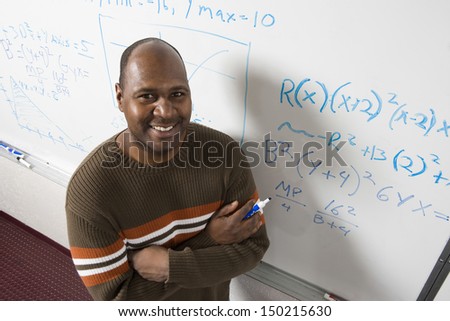 High angle portrait of confident teacher solving math\'s equations on whiteboard in classroom
