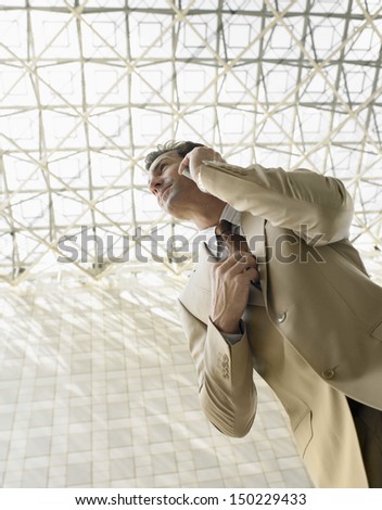 Low angle view of businessman using mobile phone under ceiling