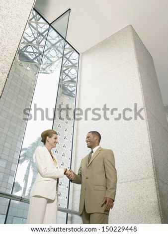 Low angle view of businesspeople shaking hands in office building
