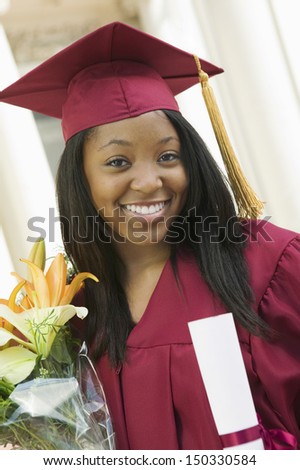 Portrait of happy female student with certificate and flower bouquet on graduation day