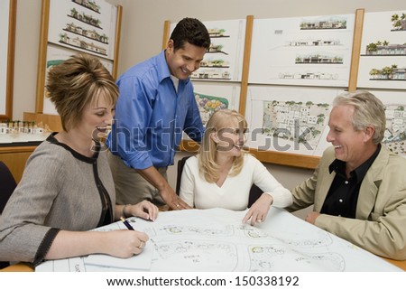 Happy couple and architects discussing plan for new house in office