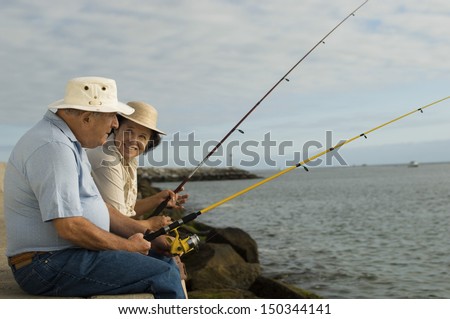 Side view of happy senior couple fishing at the beach