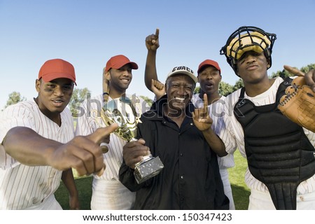 Portrait of baseball team and coach with trophy celebrating victory outdoors