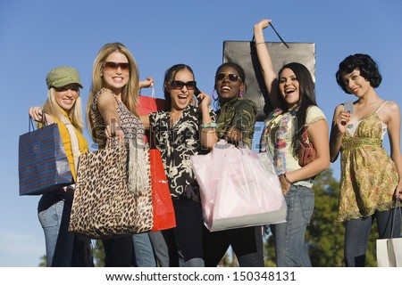 Group of multiethnic young women carrying shopping bags outdoors