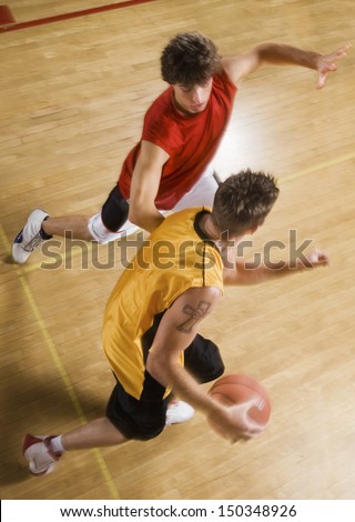 High angle view of two young men playing basketball on indoor court