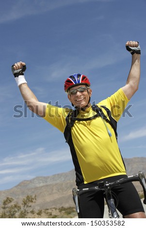 Portrait of senior man riding bicycle and cheering outdoors