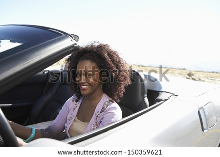 Portrait of smiling African American woman driving convertible on desert road