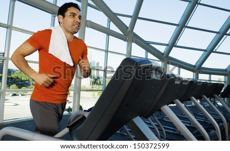 Man Looking Away While Exercising On Treadmill In Gym