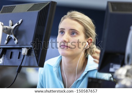Female university student using computer while listening to music in college