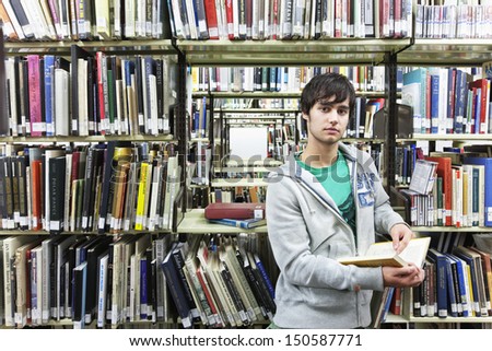Portrait of a young male university student against bookshelf in library
