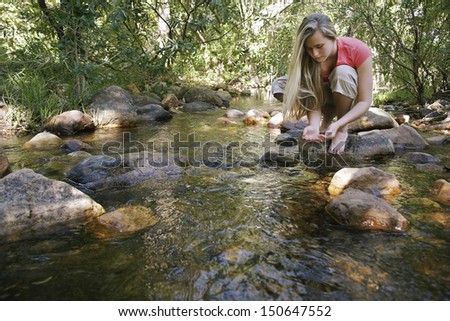 Young Woman Testing Water in Creek