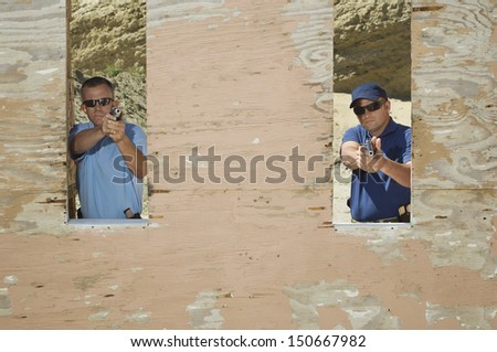 Two men aiming hand guns at firing range