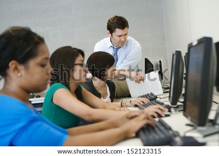 Teacher Helping Student In Computer Lab