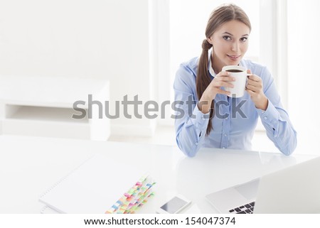 Beautiful woman drinking coffee at her desk