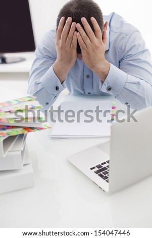 Close-up view of Caucasian businessman with heads in hands at his desk