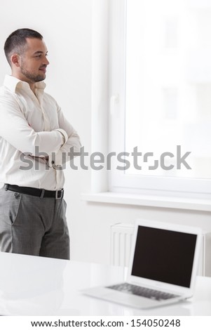 Businessman staring out of window with laptop in foreground