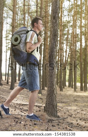 Full length side view of male hiker with backpack walking in forest
