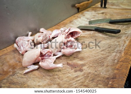 Raw chicken pieces and butcher knife on cutting board in store