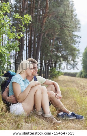 Romantic hiking couple looking away while relaxing in forest