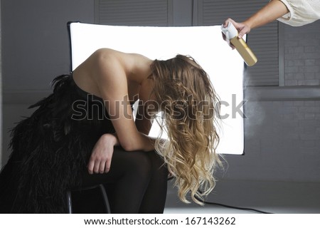 Hairstylist spraying hair product on model\'s hair
