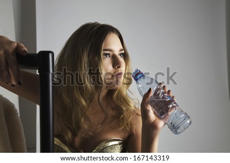 Fashion model drinking water from bottle in studio