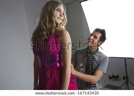Designer adjusting fashion model\'s dress in studio
