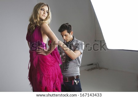 Designer adjusting dress on fashion model in studio