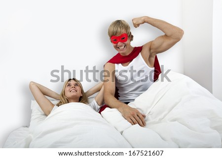 Portrait of man in superhero costume with woman on bed