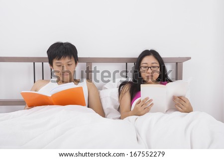 Asian couple reading books in bed