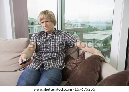 Relaxed mid-adult man watching television on sofa at home