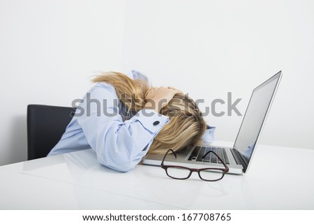 Tired businesswoman resting head on laptop in office