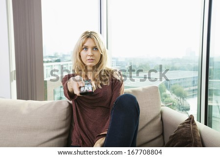 Portrait of blue eyed woman watching television on sofa at home