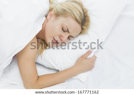Young woman in pain lying on bed