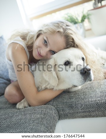 Beautiful woman hugging dog on sofa