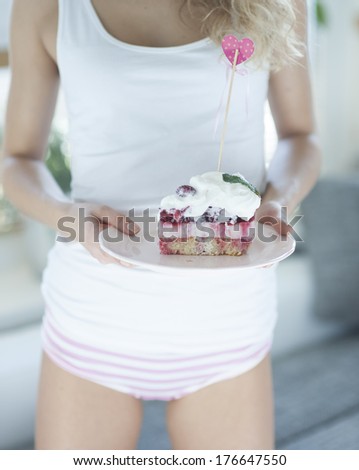 Mid section of woman with raspberry cake in house