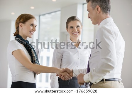 Happy business partners shaking hands in office