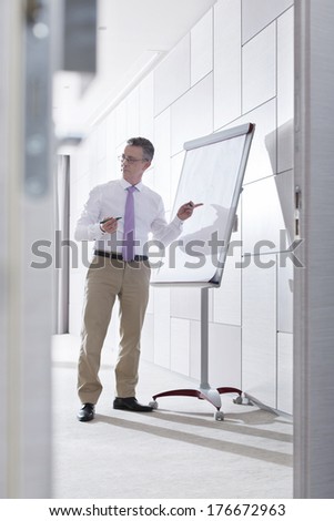 Businessman preparing for presentation on flipchart in office