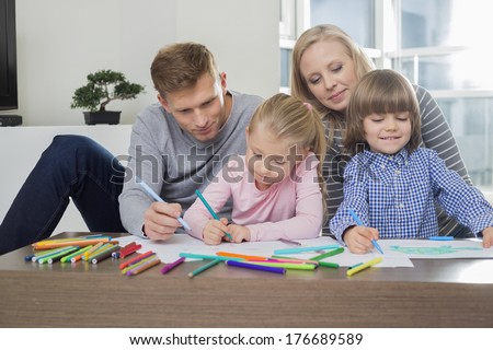 Mid adult parents with children drawing together at home
