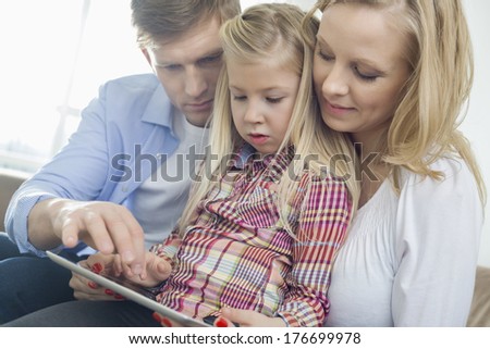 Parents and daughter using tablet computer in living room