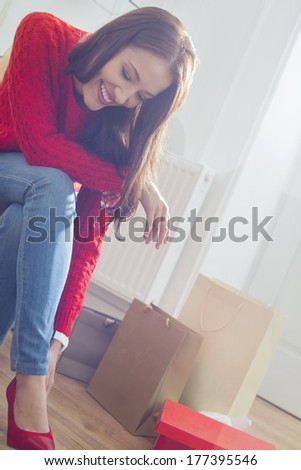 Happy young woman trying on footwear in store